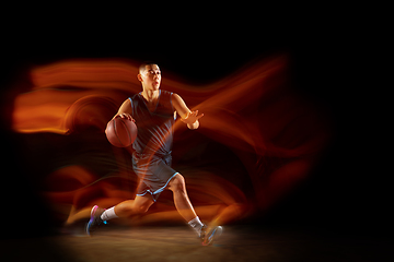 Image showing Young east asian basketball player in action and jump in mixed light over dark studio background. Concept of sport, movement, energy and dynamic, healthy lifestyle.