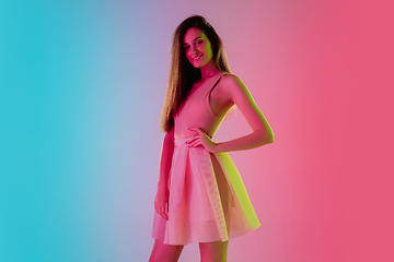 Image showing Beautiful seductive girl in fashionable, romantic outfit on bright gradient pink-blue background in neon light