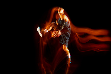 Image showing Young east asian basketball player in action and jump in mixed light over dark studio background. Concept of sport, movement, energy and dynamic, healthy lifestyle.