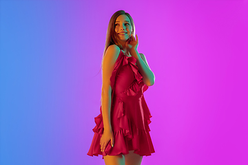 Image showing Beautiful seductive girl in fashionable, romantic outfit on bright gradient purple-blue background in neon light