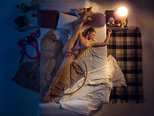 Image showing Top view of young professional rhythmic gymnast sleeping at her bedroom in sportwear with hoola hoop.