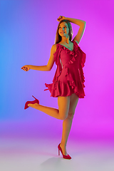 Image showing Beautiful happy girl in fashionable, romantic outfit on bright gradient purple-blue background in neon light