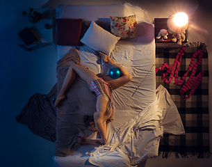 Image showing Top view of young professional rhythmic gymnast sleeping at her bedroom in sportwear with blue ball.