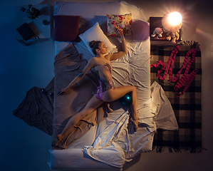 Image showing Top view of young professional rhythmic gymnast sleeping at her bedroom in sportwear with blue ball.