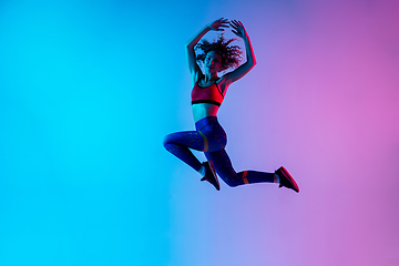 Image showing Portrait of young beautiful woman in bright sportwear isolated on gradient pink-blue studio background in neon light.