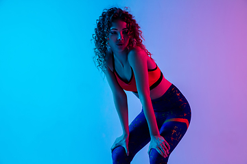 Image showing Portrait of young beautiful woman in bright sportwear isolated on gradient pink-blue studio background in neon light.