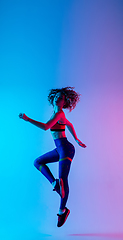 Image showing Portrait of young beautiful woman in bright sportwear isolated on gradient pink-blue studio background in neon light.