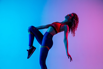 Image showing Portrait of young beautiful woman in bright sportwear isolated on gradient pink-blue studio background in neon light.