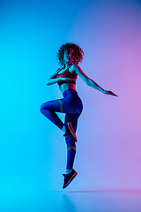 Image showing Portrait of young beautiful woman in bright sportwear isolated on gradient pink-blue studio background in neon light.