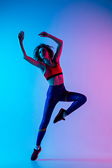 Image showing Portrait of young beautiful woman in bright sportwear isolated on gradient pink-blue studio background in neon light.