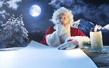 Image showing Emotional Santa Claus congratulating with New Year and Christmas, writing a letter, wish list in midnight with candle