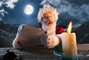 Image showing Emotional Santa Claus congratulating with New Year and Christmas, sending a letter, wish list in midnight with candle