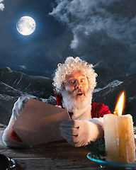 Image showing Emotional Santa Claus congratulating with New Year and Christmas, sending a letter, wish list in midnight with candle
