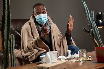 Image showing Man wrapped in a plaid wearing face mask trying to protect from somebody\'s sick