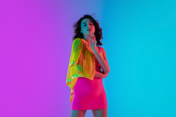 Image showing Portrait of beautiful seductive girl in fashionable bright outfit on colour gradient pink-blue background in neon light.