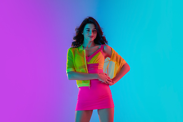 Image showing Portrait of beautiful seductive girl in fashionable bright outfit on colour gradient pink-blue background in neon light.