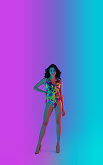 Image showing Beautiful seductive girl in fashionable bright swimsuit on colour gradient pink-blue background in neon light.