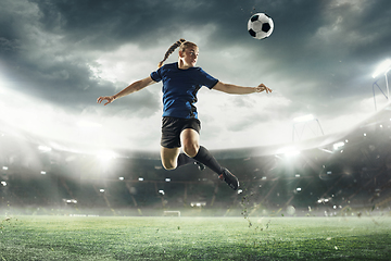 Image showing Female football or soccer player kicking ball in jump at stadium - motion, action, activity concept. Flyer for ad, design.