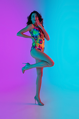 Image showing Beautiful seductive girl in fashionable bright swimsuit on colour gradient pink-blue background in neon light.