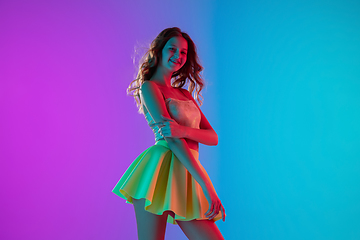 Image showing Portrait of beautiful seductive girl in fashionable bright outfit on colour gradient pink-blue background in neon light.