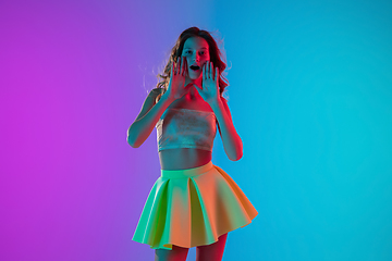 Image showing Portrait of beautiful seductive girl in fashionable bright outfit on colour gradient pink-blue background in neon light.