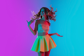 Image showing Portrait of beautiful seductive girl in fashionable bright outfit on colour gradient pink-blue background in neon light.