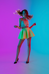 Image showing Portrait of beautiful seductive girl in fashionable bright outfit on colour gradient pink-blue background in neon light.