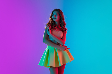 Image showing Beautiful seductive girl in fashionable bright outfit posing on colour gradient pink-blue background in neon light.