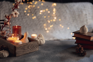 Image showing Burning candles in the wooden box isolated on grey and white background with garland lights. Greeting card design.