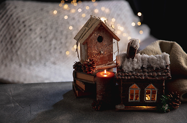 Image showing Miniatures of houses isolated on grey and white background with garland lights. The concept of home atmosphere and comfort.