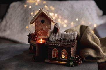 Image showing Miniatures of houses isolated on grey and white background with garland lights. The concept of home atmosphere and comfort.