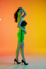 Image showing Portrait of beautiful seductive girl in fashionable, modern outfit on bright gradient background in neon light