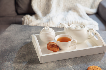 Image showing White wooden tray with tea set on grey table. The concept of home atmosphere and comfort.