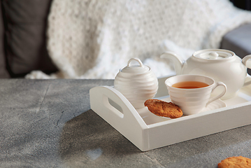 Image showing White wooden tray with tea set on grey table. The concept of home atmosphere and comfort.