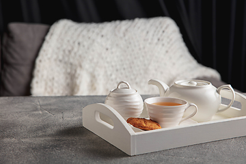 Image showing White wooden tray with tea set and miniature of house isolated on grey and white background.