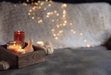 Image showing Burning candles in the wooden box isolated on grey and white background with garland lights. Greeting card design.