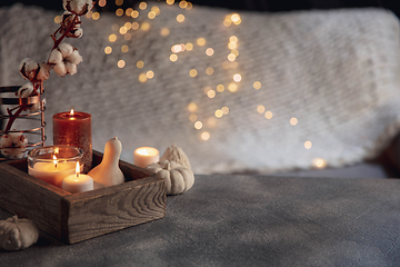 Image showing Burning candles in the wooden box isolated on grey and white background with garland lights. Greeting card design.