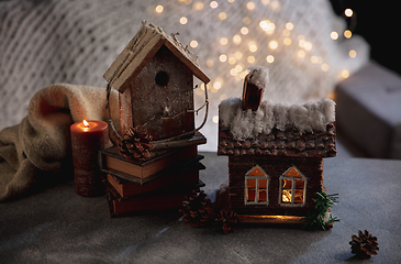 Image showing Miniatures of houses isolated on grey and white background with garland lights. The concept of home atmosphere and comfort.