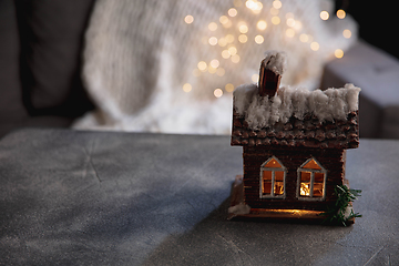 Image showing House miniature illuminated against grey background. Cozy winter, snowing. Copy space for ad, design.