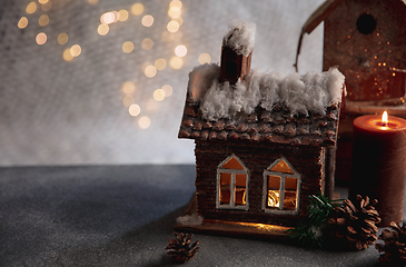 Image showing Miniatures of houses isolated on grey and white background with garland lights. The concept of home atmosphere and comfort.