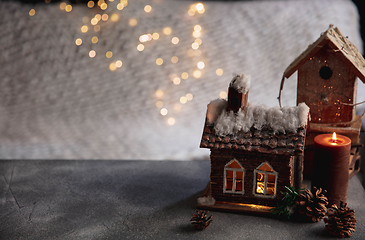 Image showing Miniatures of houses isolated on grey and white background with garland lights. The concept of home atmosphere and comfort.