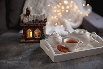 Image showing White wooden tray with tea set and miniature of house isolated on grey and white background.