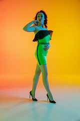 Image showing Portrait of beautiful seductive girl in fashionable, modern outfit on bright gradient background in neon light