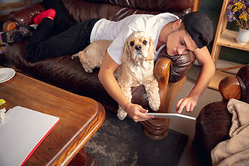 Image showing Young Caucasian man and his pet American Cocker Spaniel cream colour have a rest at home. Top view.