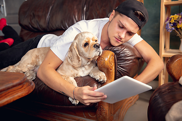 Image showing Close up young Caucasian man and his pet American Cocker Spaniel cream colour have a rest at home.