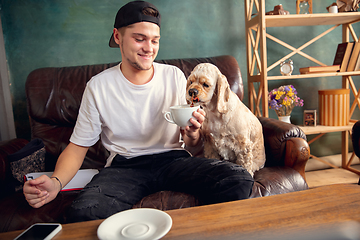 Image showing Two best friends young man and American Cocker Spaniel cream colour drink tea at home.