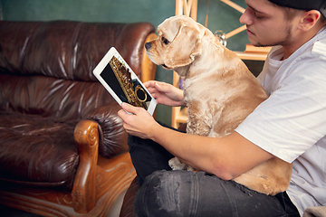 Image showing Young Caucasian man and his pet American Cocker Spaniel cream colour have a rest at home.