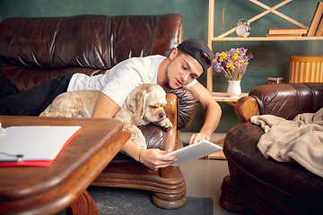 Image showing Young Caucasian man and his pet American Cocker Spaniel cream colour have a rest at home.