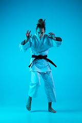 Image showing Young girl professional judoist isolated on blue studio background in neon light. Healthy lifestyle, sport concept.