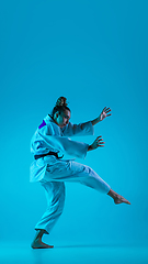 Image showing Young girl professional judoist isolated on blue studio background in neon light. Healthy lifestyle, sport concept.